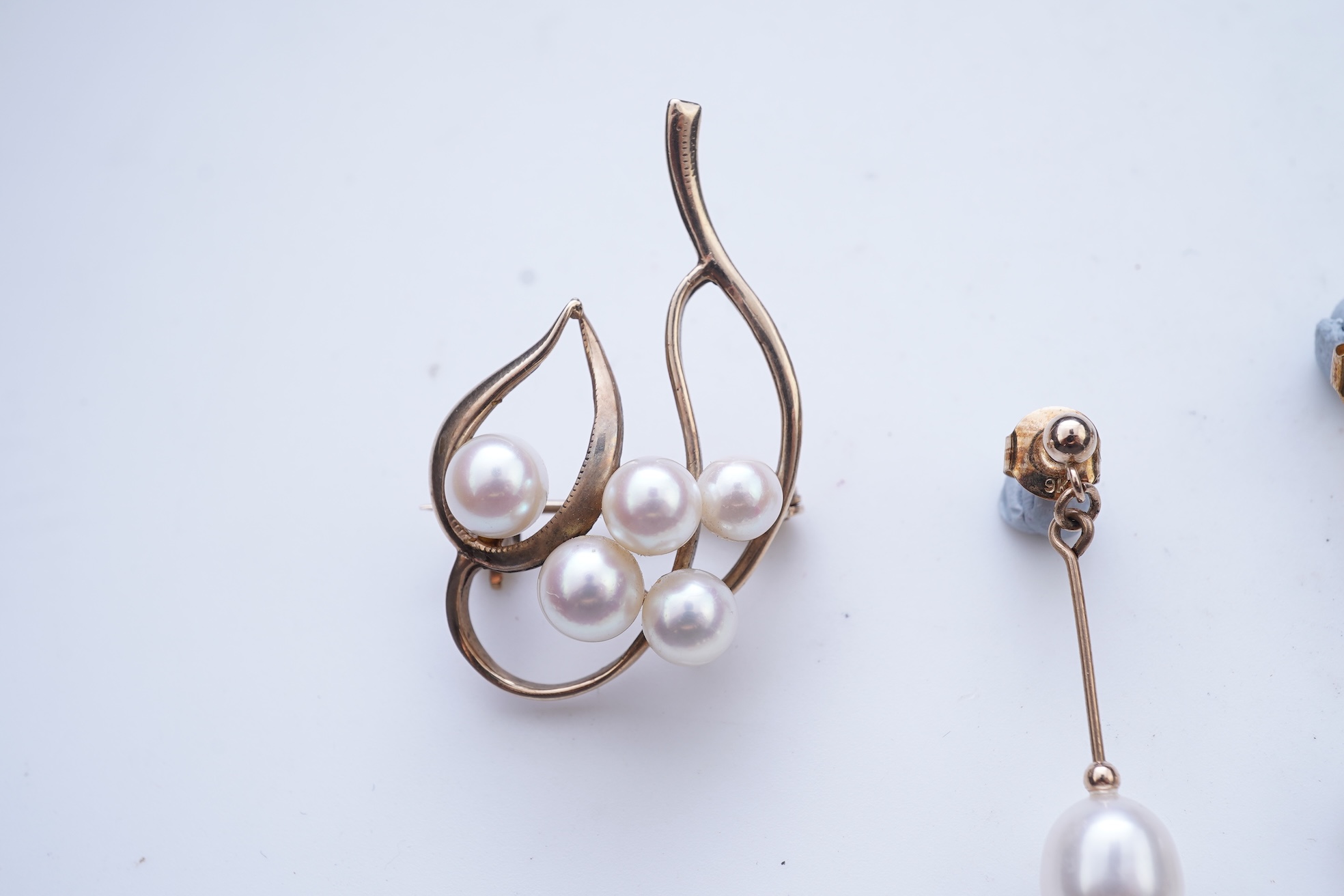 A group of cultured pearl jewels, comprising: two pairs of cultured pearl drop earrings, longest 3cm, mounted in gold; and two cultured pearl brooches mounted in 9ct gold, longest 4.1cm, British hallmarks, combined gross